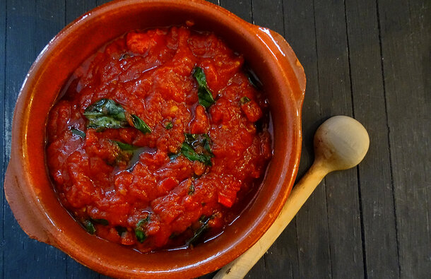 A deep rich looking tomato and basil sauce is a deep red colour with specs of green basil. 