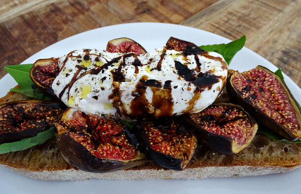 The open sandwich is full of contrasting colours: jammy red figs and fresh green basil leaves